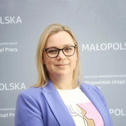 blondynka w okularach, włosy proste do ramion, t-shirt z kolorowym graficznym nadrukiem i marynarka