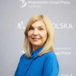 uśmiechnięta blondynka w średnim wieku z włosami do ramion, w ciemnej gładkiej bluzce