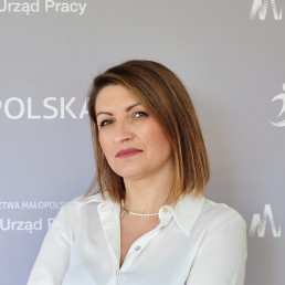 szatynka z prostymi włosami za ucho ubrana w białą koszulę