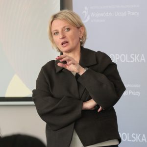 Młoda blondynka mówi gestykulując.