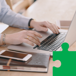 w centrum leży laptop, na który ktoś pisze. Obok leży kalendarz, notatnik, a na nim telefon