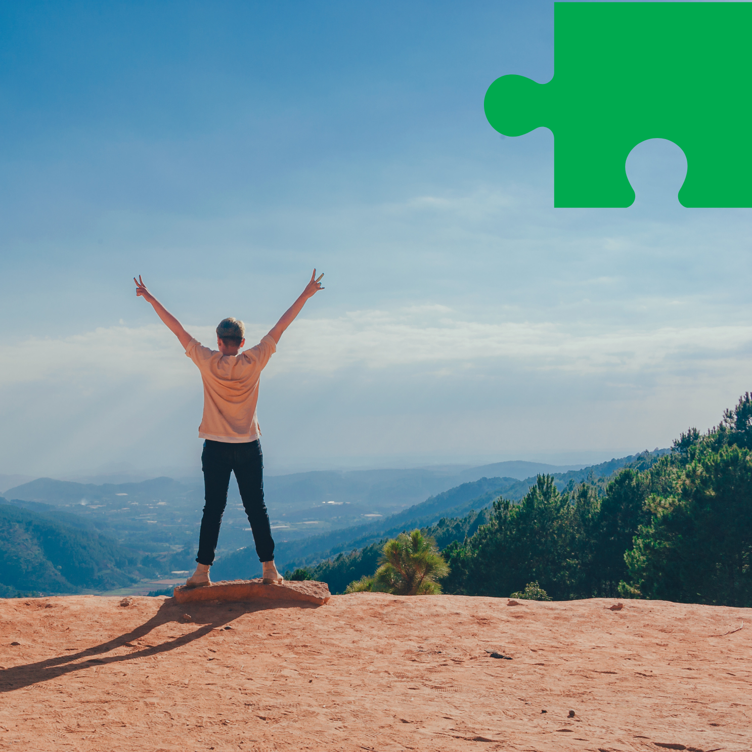 Człowiek z uniesionymi rękami, na horyzoncie drzewa i pasma górskie.