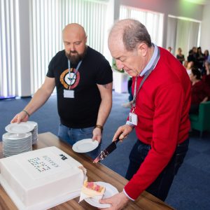 Dwaj mężczyźni nakładają sobie kawałki tortu z napisem EXPO Kraków.