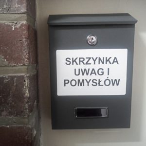 Zbliżenie na wiszącą na ścianie skrzynkę na listy, na której znajduje się napis: "Skrzynka uwag i pomysłów".