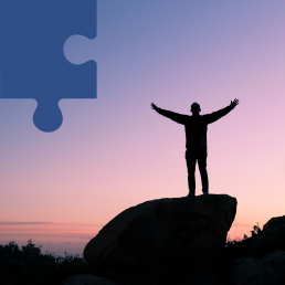 Na tle zachodzącego słońca widoczna jest sylwetka mężczyzny z rozłożonymi rękami.