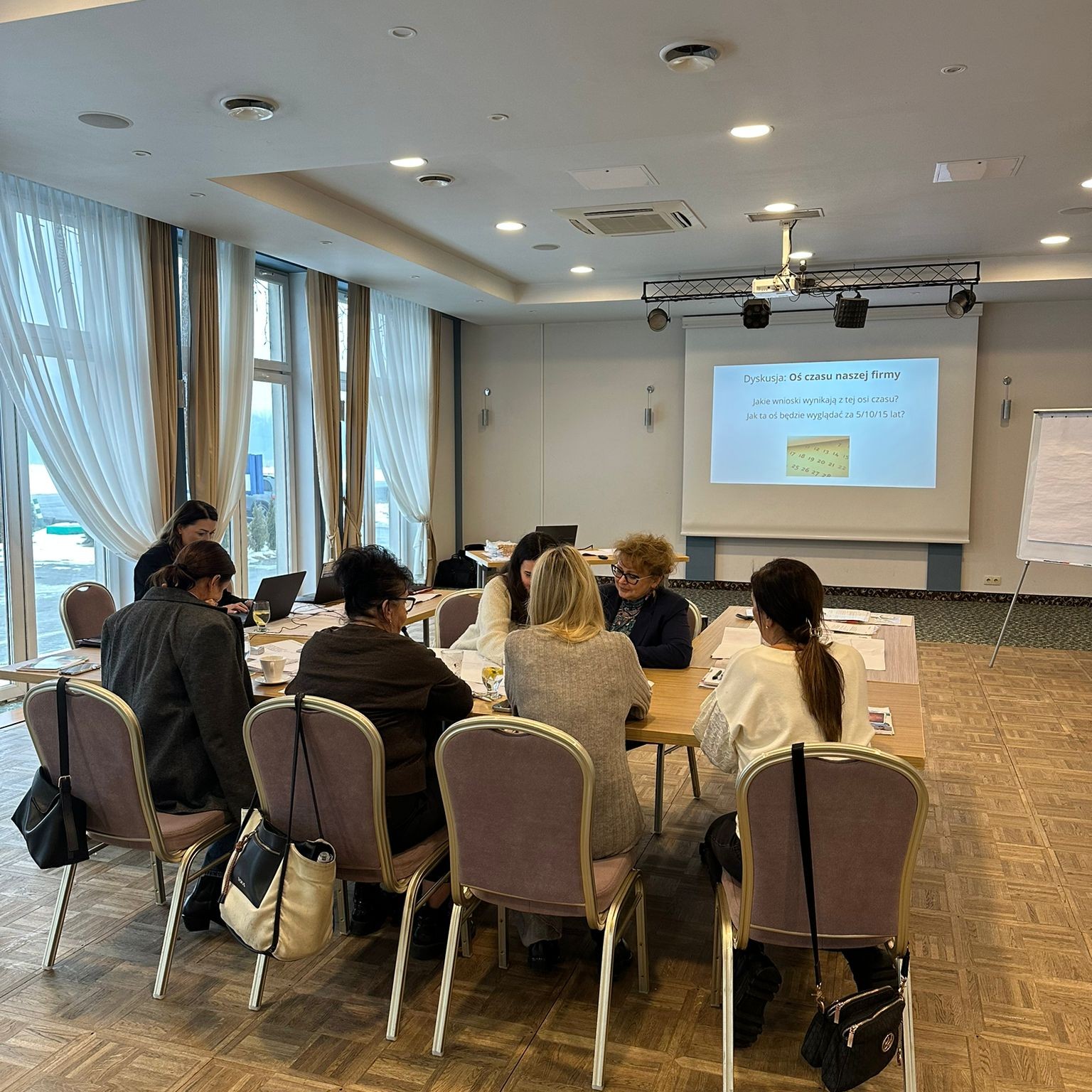 Grupa kobiet pracuje wspólnie przy stole na szkoleniu.