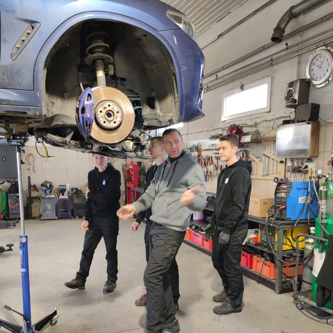 Mężczyzna w średnim wieku stoi przy samochodzie z trzema młodymi.