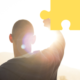 Młody mężczyzna odwrócony tyłem unosi rękę w górę w geście zwycięstwa.