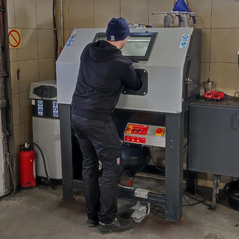 Młody mężczyzna pracuje przy maszynie.