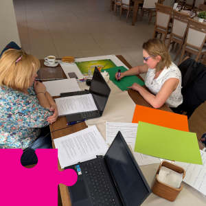 Dwie osoby siedzą przy stole, na stole dwa laptopy i dokumenty