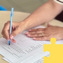 Na stole leżą dokumenty, przed nią siedzi osoba widać ręcę i długopis, w geście podpisywania umowy